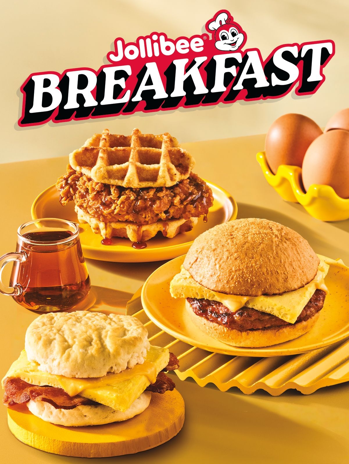 A sausage, egg, and cheese biscuit, longanisa breakfast sandwich, and chicken and waffles sandwich with the Jollibee logo and 'BREAKFAST' text on yellow background